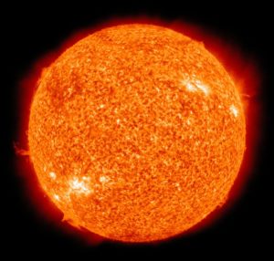 The sun, glowing orange, bright sunspots visible, surrounded by black space