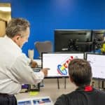 two employees pointing at a computer screen discussing laser peening solutions