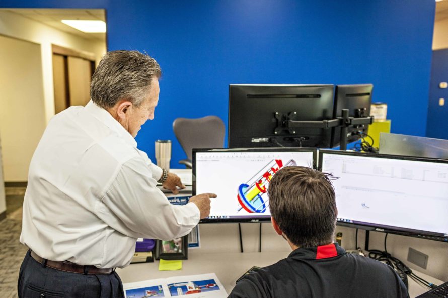 two employees pointing at a computer screen discussing laser peening solutions