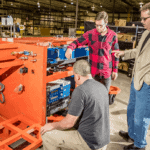 Three engineers working on laser peening machinery.